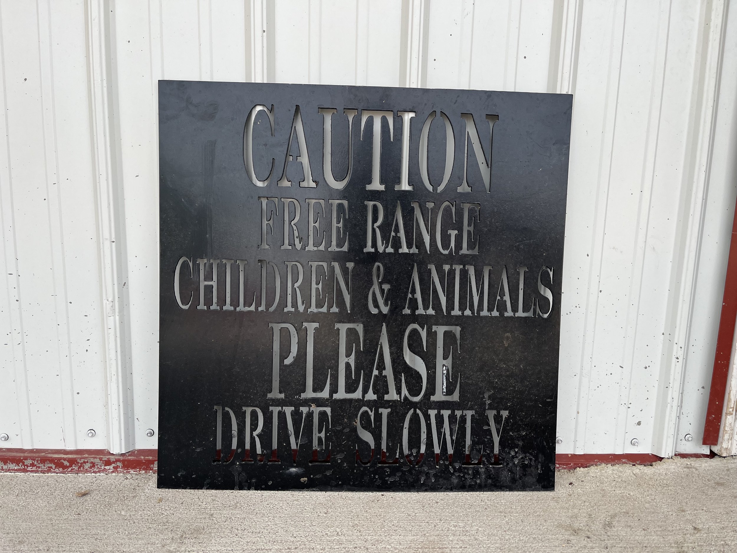 caution+sign (1) Black caution sign warning drivers to be mindful of free-range children and animals, with instructions to drive slowly.