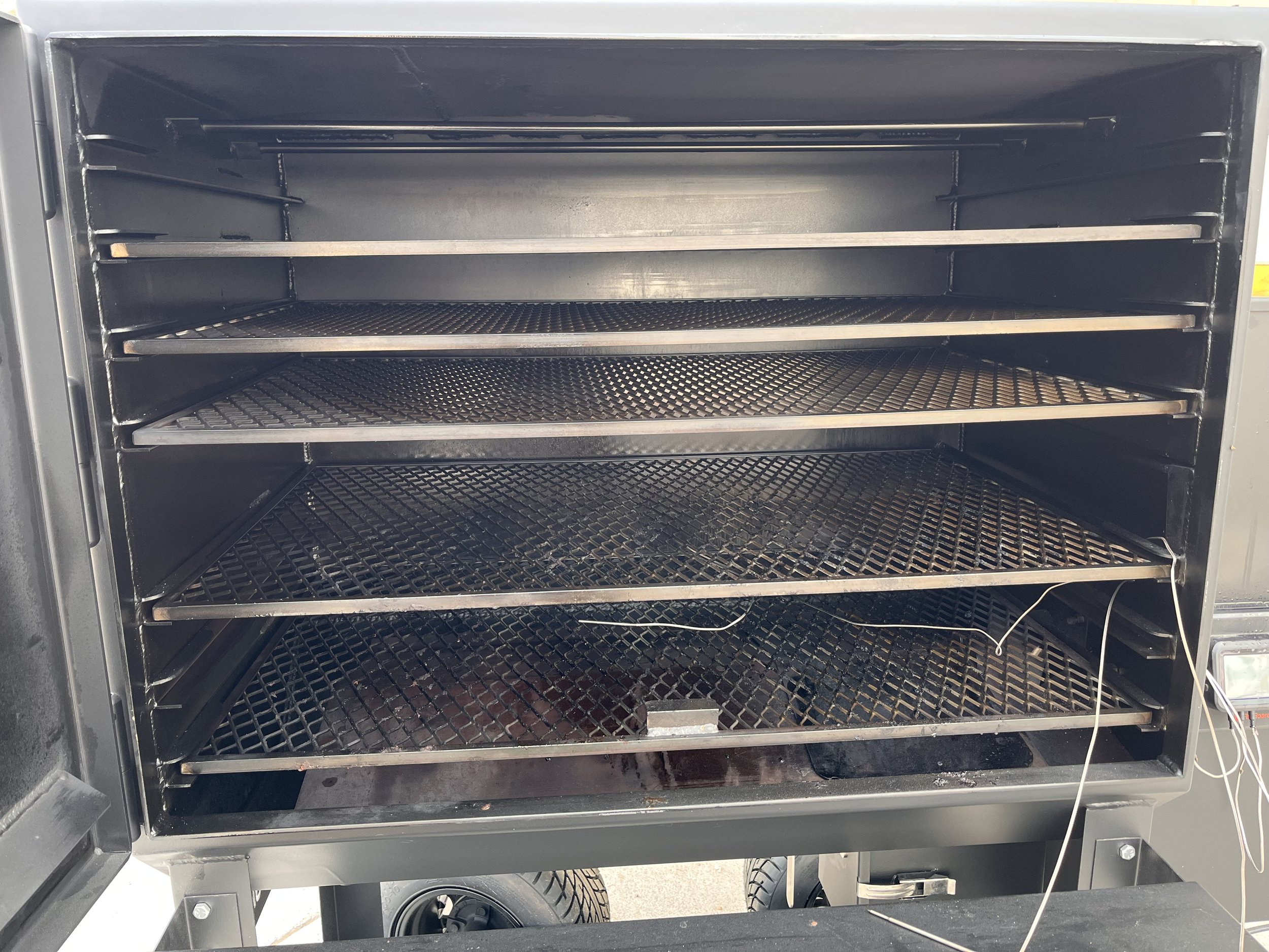 inside+smoker Interior view of a commercial smoker with multiple metal racks for cooking, showcasing a spacious design suitable for barbecuing and smoking meats.